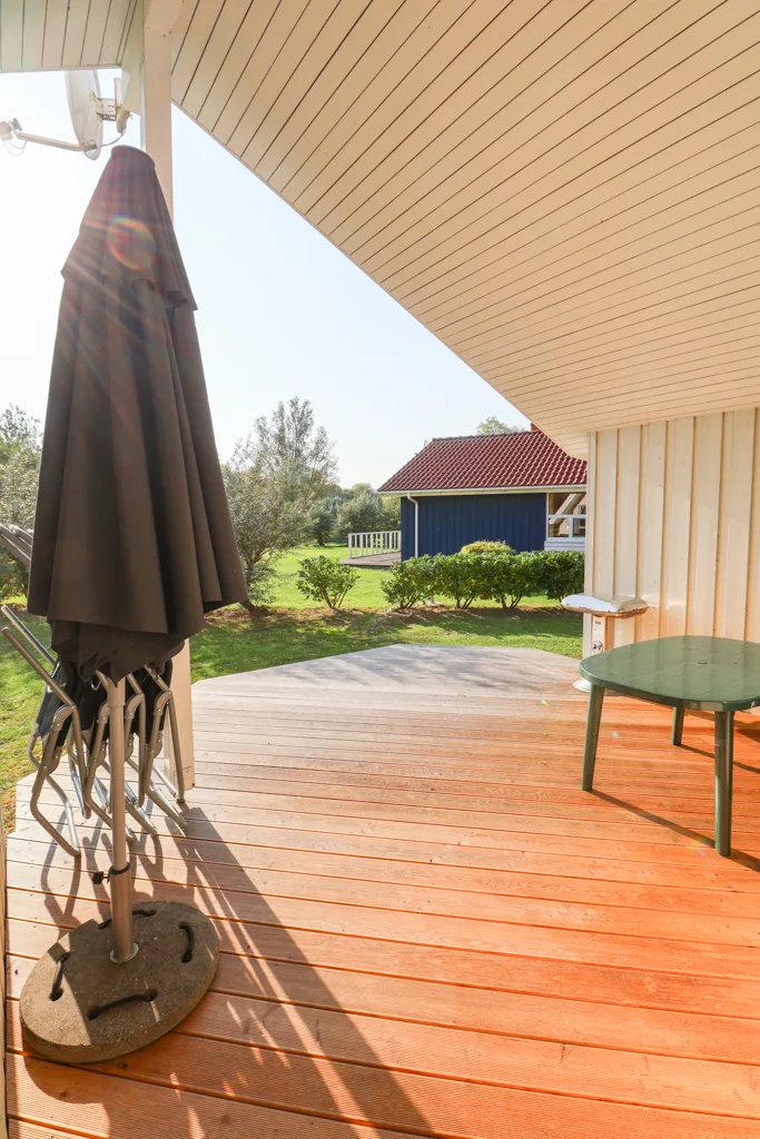 Überdachte Holzterrasse des Fjordhauses mit Blick in den Garten